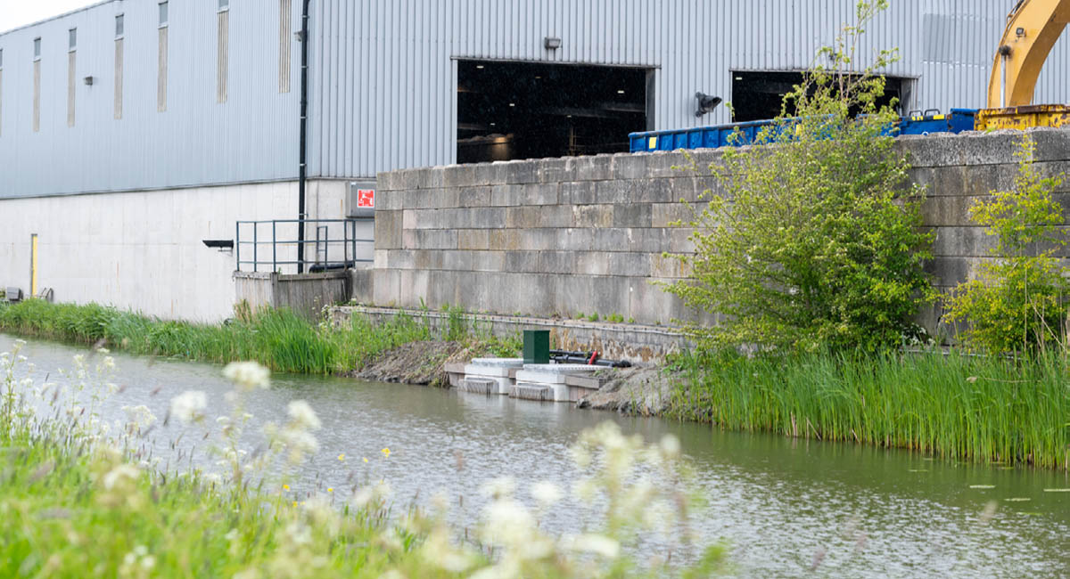 Foto van putten met schakelkast en pompen aan de oever bij Renewi